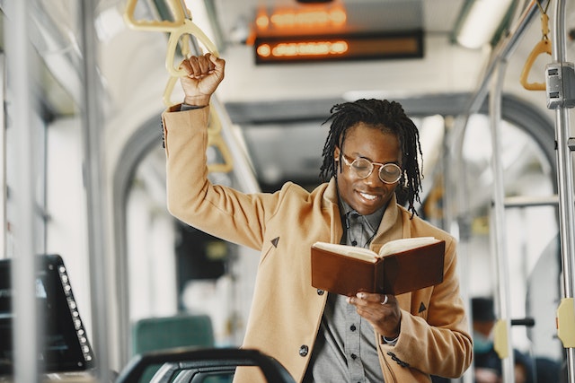 person standing on a bus while reading a book